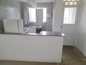 a kitchen with a counter and a white refrigerator at KIT Rayar in Alto Paraíso de Goiás