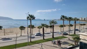 a view of the beach and palm trees from a building at Luxury Two Bedrooms and two balcony beachfront apartment in Vlorë