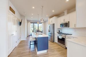 a kitchen with white cabinets and a blue island at Lake George Getaway in Lake George