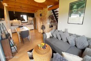 un salon avec un canapé gris et une cuisine dans l'établissement Holiday home with garden, sauna, jacuzzi, à Mielenko