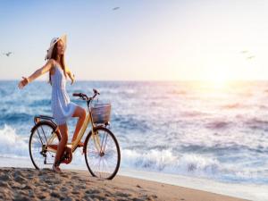 a woman in a dress riding a bike on the beach at Holiday home with garden, close to the beach in Sarbinowo