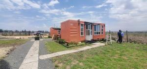 an orange tiny house sitting on top of a field at Acacia Square & Camping in Kitengela 
