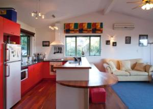 a kitchen with red cabinets and a white refrigerator at Kereru Hill in Palm Beach