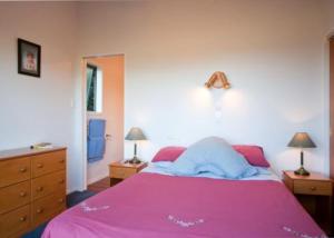 a bedroom with a pink bed with two night stands at Kereru Hill in Palm Beach