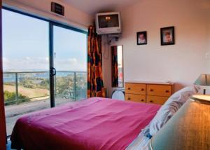 a bedroom with a bed and a large window at Kereru Hill in Palm Beach