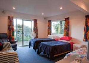 a bedroom with two beds and a couch at Kereru Hill in Palm Beach