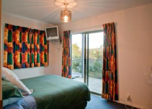 a bedroom with a bed and a window with a balcony at Kereru Hill in Palm Beach +2 photos