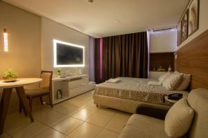 a bedroom with a bed and a table and a desk at Suíte luxo com tela de cinema no América Towers Studio Residence in Salvador