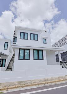 a white house with black windows on a street at Elegant Home with KingBed Private Patio Ensuites in San Juan