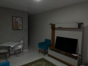 a living room with a tv and a table with chairs at Casa Piscina Guaratuba 400mt praia in Guaratuba