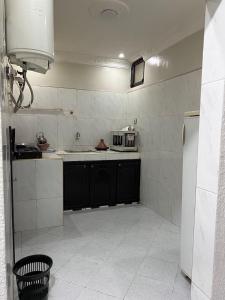 a kitchen with black cabinets and a white tile wall at Relaxing stay in a quiet apartment in Laayoune