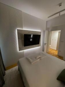 ein Schlafzimmer mit einem Bett mit einem Flachbildfernseher an der Wand in der Unterkunft Limak's Diamond Residences in Skopje + 54 Fotos