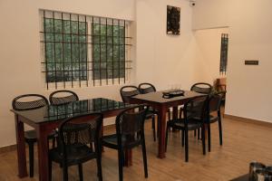 una sala da pranzo con tavoli e sedie e una finestra di Pallakki Comforts Chikmagalur a Attigundi