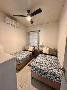 a bedroom with two beds and a ceiling fan at VILLA MORÁN, a Dream Home Sonsonate in Sonsonate