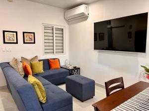 a living room with a blue couch and a tv at VILLA MORÁN, a Dream Home Sonsonate in Sonsonate