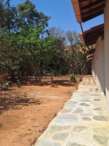 ein Gehweg neben einem Gebäude mit Bäumen im Hintergrund in der Unterkunft Suítes Recanto das Flores 2 in Pirenópolis