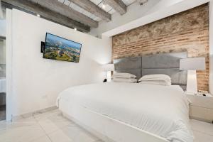 ein Schlafzimmer mit einem weißen Bett und einer Backsteinwand in der Unterkunft Upper Hotel in Cartagena de Indias