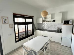 a kitchen with a white table and a white refrigerator at Farito Sunset in Gáldar +17 photos