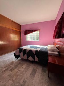 une chambre avec un lit et un mur rose dans l'établissement Chalet 1 hectárea junto al río y montaña a 20 min de Orizaba, à Nogales