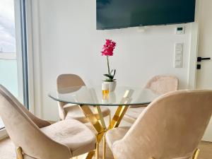 una mesa de cristal con sillas y un jarrón con una flor en ASP Modern Apartments with Balcony & Free Parking, en Viena