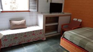 a room with a bed and a desk with a television at Casa 85 m2 no FORTE 2 quartos campinho piscinas 2 vagas no estacionamento portaria ar condicionado para 8 pessoas in Itamaracá +19 photos