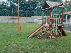 a playground with a wooden slide in a park at Casa 85 m2 no FORTE 2 quartos campinho piscinas 2 vagas no estacionamento portaria ar condicionado para 8 pessoas in Itamaracá