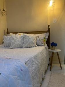 a bed with a white comforter and a side table at Apartamento piuma in Piúma
