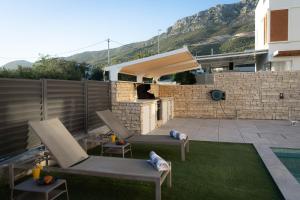 a patio with two chairs and a grill in a backyard at TI Amo Holiday House - Heated Pool in Kaštela