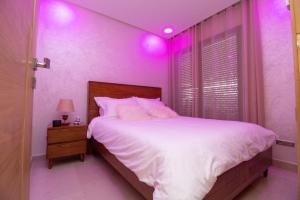 a bedroom with a bed with pink lights on it at Studio élégant et neuf près de la gare tgv in Casablanca +12 photos