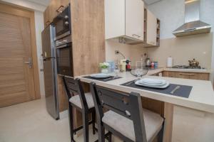 a kitchen with a counter with two chairs and a table at Studio élégant et neuf près de la gare tgv in Casablanca