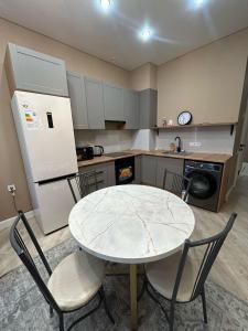 a kitchen with a table and chairs and a refrigerator at Perfect HoLiDaY in Almaty +8 photos