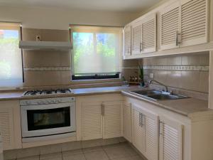 Una cocina con gabinetes blancos, un fregadero y una estufa. en Villa 10, en Mazatlán