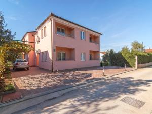 une maison rose avec une voiture garée devant elle dans l'établissement Apartments Alen, à Fažana