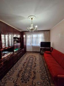 sala de estar con sofá rojo y lámpara de araña en Подобова для Дорогова, en Izyum