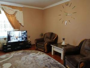 sala de estar con 2 sillas y reloj en la pared en Подобова для Дорогова, en Izyum
