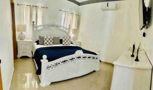 a bedroom with a white bed with a blue blanket at Hermosa Casa familiar en las orquideas LR in La Romana