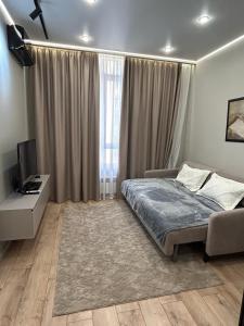 ein Schlafzimmer mit einem Bett, einem Schreibtisch und einem Fernseher in der Unterkunft Royal Comfort Business Class Apartment in the heart of the ALMATY CITY in Almaty