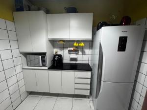 une cuisine avec des armoires blanches et un réfrigérateur dans l'établissement Aluguel de Apt na COP30, à Benjamim