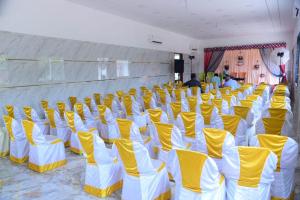 une pièce avec des chaises jaunes et blanches dans l'établissement Royal gardens party Hall, à Wālājāpet