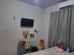 ein Schlafzimmer mit einem Fernseher an der Wand und einem Bett in der Unterkunft Alex in Castanhal