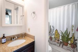 a bathroom with a sink and a shower curtain with cactus at North PB Gem Close to the Beach in San Diego +34 photos