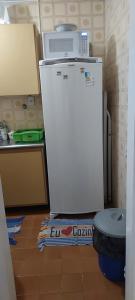 a refrigerator in a kitchen with a microwave on top of it at Apto aconchegante pitangueiras in Guarujá