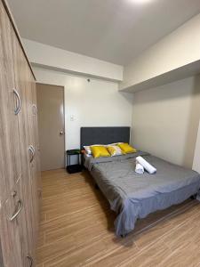 Biñanにある1Bedroom, living room w balcony ADHI staycationの黄色い枕が置かれたベッドのある寝室