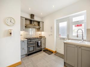a kitchen with stainless steel appliances and a clock on the wall at The Nook in Chapel Saint Leonards