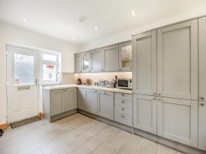 a white kitchen with white cabinets and a window at The Nook in Chapel Saint Leonards +24 photos