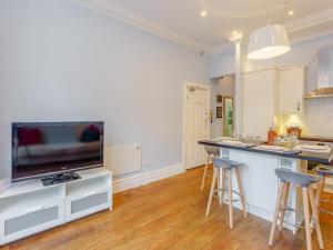 a kitchen with a tv and a counter with stools at Viking Bay Apartment in Broadstairs