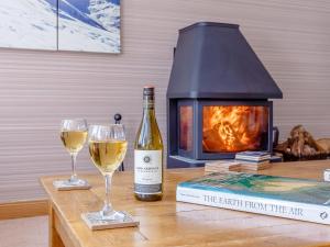 a bottle of wine and two glasses on a table with a fireplace at The Lookout in Aviemore