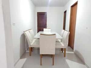 a dining room with a white table and chairs at Casa no centro de Japaratinga in Japaratinga