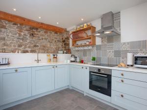 una cucina con armadi bianchi e un muro in pietra di The Woodshed a Sheepwash