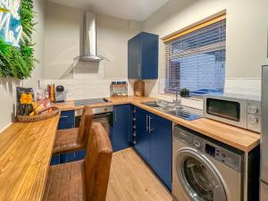 a kitchen with blue cabinets and a washer and dryer at Hogarth No 2 - Uk48955 in Newbiggin-by-the-Sea